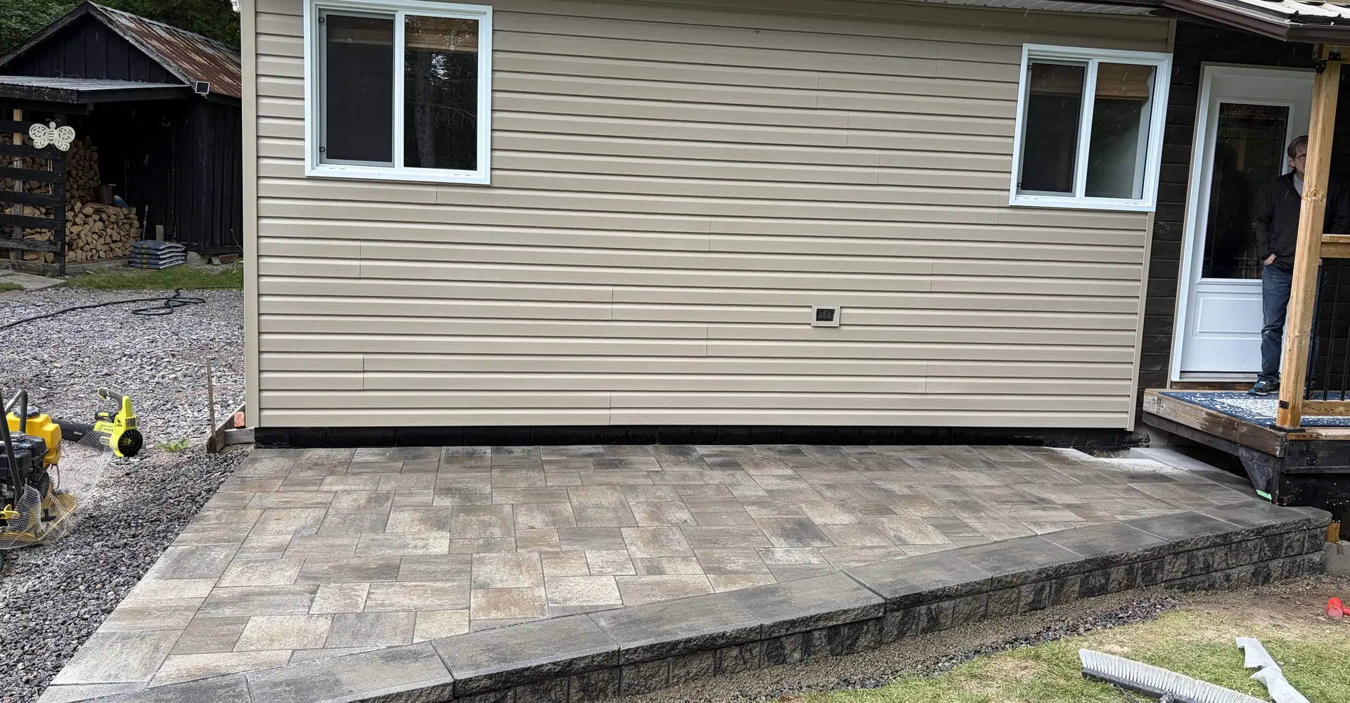 Raised paver platform and deck built against a home by Edwards Landscape and Construction in North Bay, Ontario
