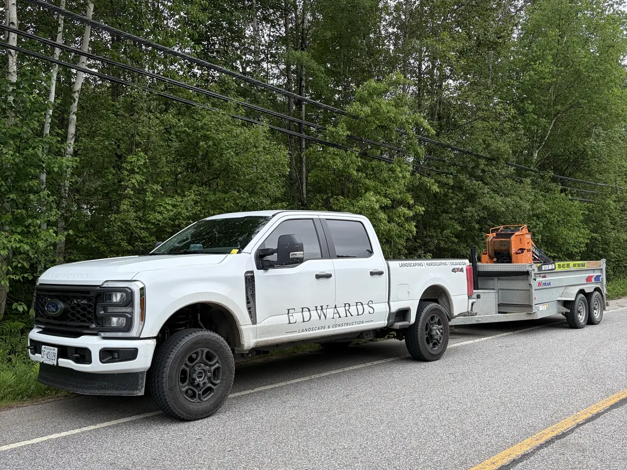 Edwards Landscape and Construction truck and trailer hauling excavation equipment near North Bay