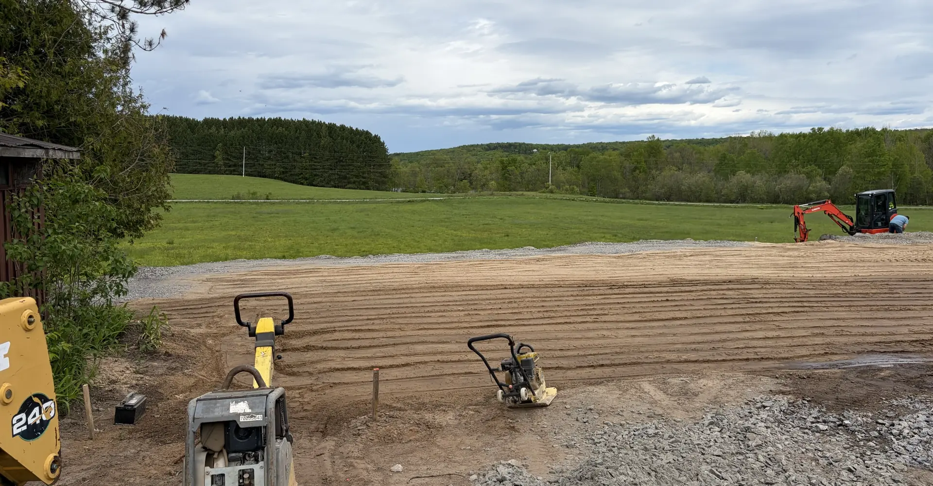 Site excavation and grading with a plate compactor and excavator by Edwards Landscape and Construction near North Bay, Ontario